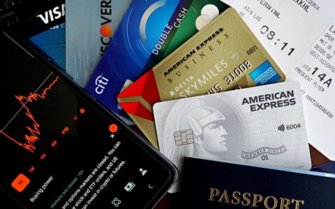 Flat lay of credit cards, passport, and a phone showing stock data, depicting finance and travel.